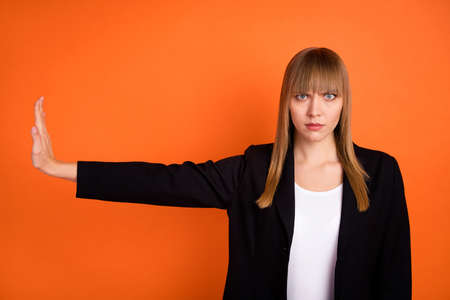 Portrait of attractive serious strict girl showing aside stop sign no isolated over bright orange color backgroundの写真素材