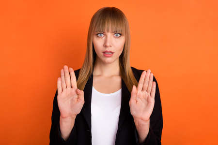 Photo of sad nice blond hair lady hands stop wear black jacket isolated on bright orange color backgroundの写真素材
