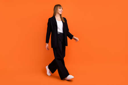 Full length body size view of attractive cheerful content girl walking office look isolated over bright orange color backgroundの写真素材