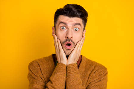 Photo of impressed person open mouth arms on cheeks staring camera cant believe isolated on yellow color backgroundの写真素材