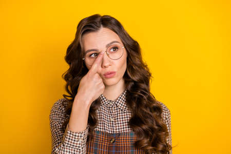 Portrait of attractive genius wavy-haired girl wear checked uniform touching specs isolated over bright yellow color backgroundの写真素材