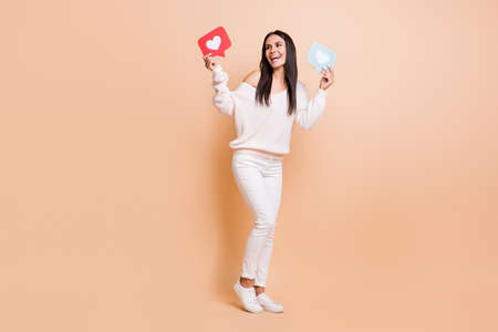 Full length photo of young girl happy smile look empty space hold paper card message info isolated over beige color backgroundの写真素材