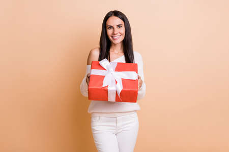 Photo of young attractive girl happy smile hold present box holiday celebration isolated over beige color backgroundの写真素材