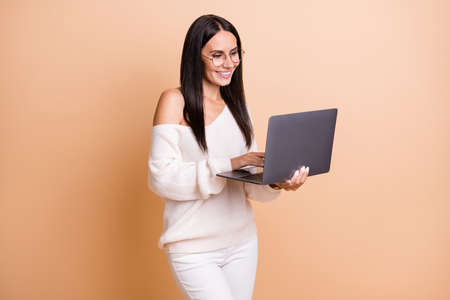 Photo of young attractive business woman happy smile browse internet laptop type email isolated over beige color backgroundの写真素材