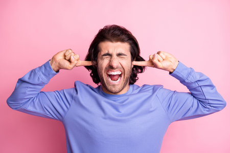 Photo of crazy irritated young man close ears fingers loun noise avoid isolated on shine pastel pink...