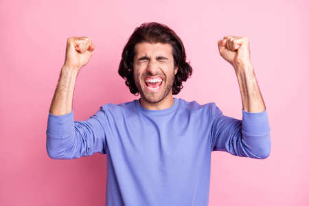 Photo of victorious handsome young man raise fists say yeah winner champion lottery isolated on pastel pink color backgroundの写真素材