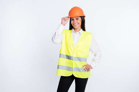 Photo of positive worker lady arm hip look camera wear helmet shirt vest isolated white color backgroundの写真素材