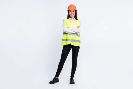 Photo of self-assured lady folded hands wear helmet shirt vest pants shoes isolated white color...
