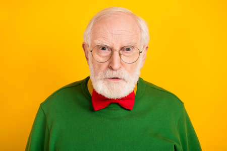Photo of angry upset mature man dressed pullover bow tie glasses isolated yellow color backgroundの写真素材
