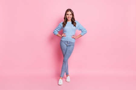 Full size photo of young happy cheerful good mood smiling girl wear blue sweater and jeans isolated on pink color backgroundの写真素材