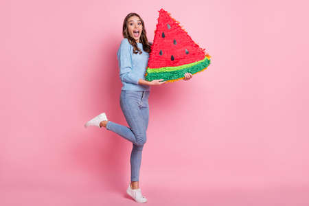 Photo of lady hold big slice watermelon figure open mouth wear blue pullover footwear jeans isolated pink backgroundの写真素材