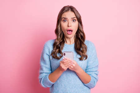 Photo of scared nervous young lady hold cellphone open mouth wear blue pullover isolated pink...