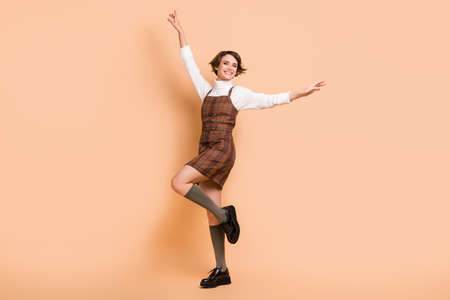 Full size photo of young beautiful attractive smiling cheerful positive woman dancing isolated on beige color backgroundの写真素材