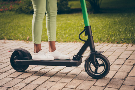 Cropped view of her she nice girls legs stranding on electric scooter gadget enjoying spending free time autumn fall season active hobby activity outside outdoor in green forestの写真素材