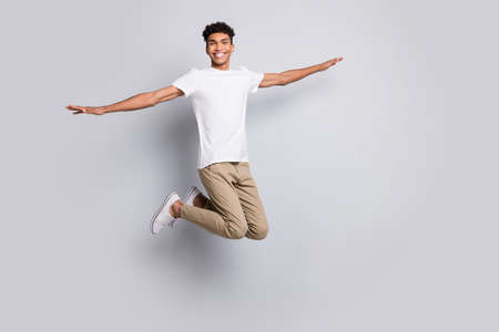 Full size profile photo of brunet optimistic nice guy jump wear white t-shirt pants isolated on grey backgroundの写真素材