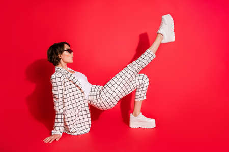 Full length profile side photo of young attractive woman posing floor enjoy look empty space isolated over red color backgroundの写真素材