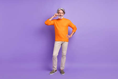Full length photo of mature man happy positive smile hand touch mustache isolated over violet color backgroundの写真素材