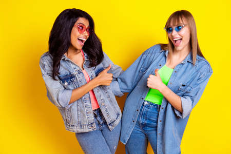 Photo of excited carefree persons open mouth look each other wear denim isolated on yellow color backgroundの写真素材