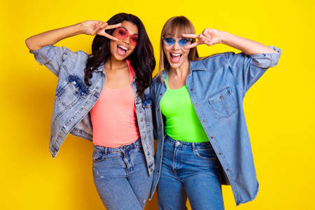 Photo of crazy funny girls diversity open mouth smile fingers show v-sign bear eye isolated on yellow color backgroundの写真素材