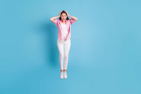 Full size photo of attractive astonished person jump arms on head open mouth isolated on blue color...