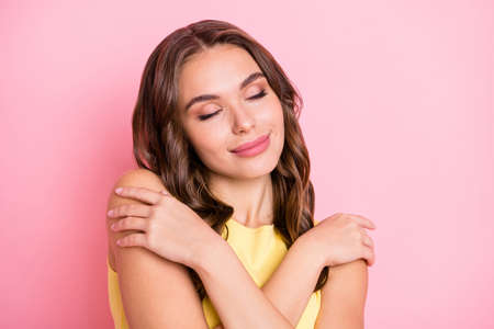 Portrait of pretty young girl closed eyes embrace shoulder imagination isolated on pink color backgroundの写真素材