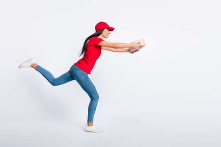 Full size profile side photo of young happy excited girl running fast deliver package isolated on grey color backgroundの写真素材