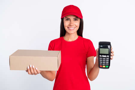 Photo of young happy cheerful smiling lovely delivery girl hold package and terminal isolated on grey color backgroundの写真素材