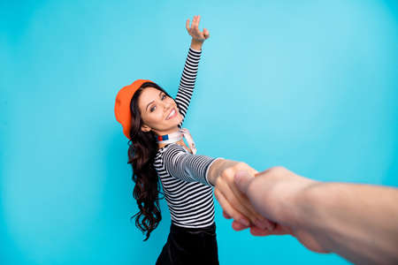 First point view portrait of charming cheerful person hold hand toothy smile isolated on blue color backgroundの写真素材