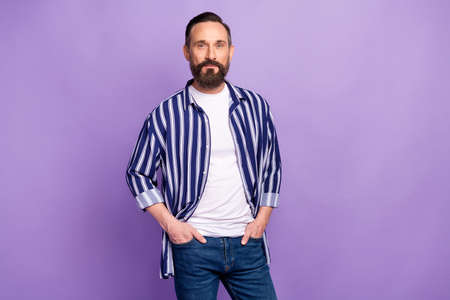 Photo of mature man put hands pockets look in camera isolated over purple color background