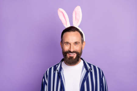 Photo of funny guy beaming white smile wear rabbit ears headband striped shirt isolated purple color...