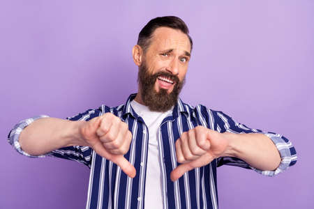 Photo of frustrated mature man dislike show thumb-down isolated over violet color backgroundの写真素材