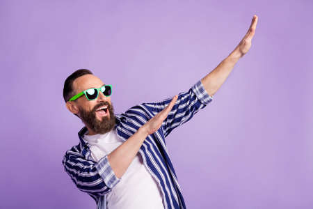 Photo of crazy funky guy look up empty space raise hands dance wear striped shirt isolated violet color backgroundの写真素材