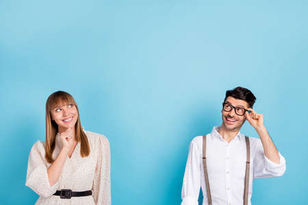 Photo of funny thoughtful young couple wear white outfit arm hand chin spectacles looking empty space isolated blue color backgroundの写真素材