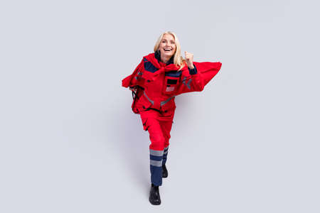 Full length photo of happy old paramedic woman wear red cape uniform smile isolated on grey color backgroundの写真素材