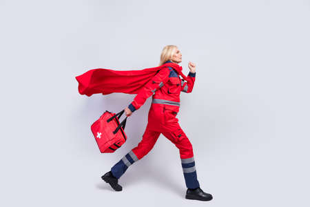 Full size profile side photo of brave serious paramedic old woman walk hold bag wear cape isolated on grey color backgroundの写真素材