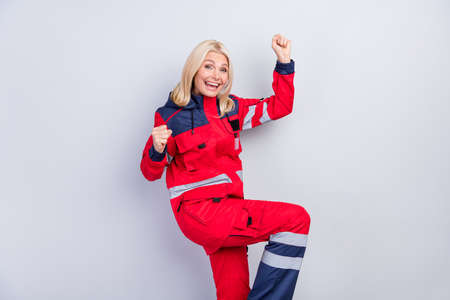 Profile photo of astonished woman fists knee up open mouth shout yes isolated on grey color backgroundの写真素材