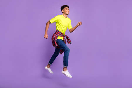 Full length profile side photo of young black guy happy smile jump go walk run hurry sale isolated over violet color backgroundの写真素材