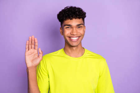 Photo of young cheerful afro man happy positive smile wave hand hello hi isolated over violet color backgroundの写真素材