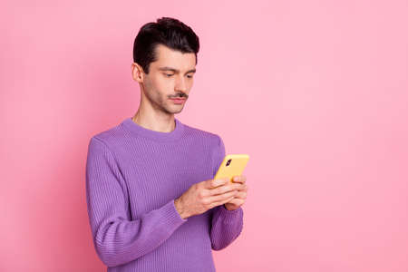 Portrait of attractive focused guy using device browsing web site smm multimedia isolated over pink pastel color backgroundの写真素材