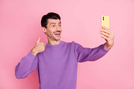 Photo of funny charming man dressed purple pullover showing thumb up tacking selfie modern device...