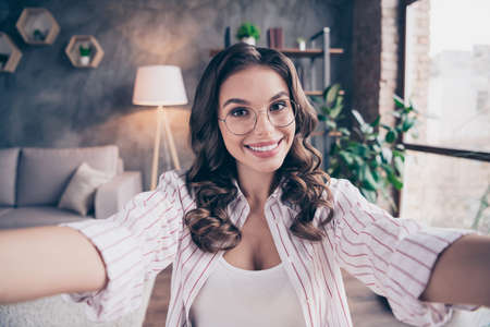 Photo of young cheerful attractive woman wear glasses happy positive smile make shooting selfie indoors homeの写真素材