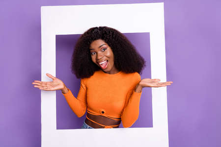 Portrait of attractive glad cheerful wavy-haired girl having fun coming paper frame isolated over purple violet pastel color backgroundの写真素材