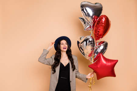 Photo portrait of woman wearing headwear keeping balloons at birthday laughing isolated on pastel...