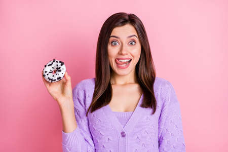 Photo of optimistic girl hold donut tongue out wear lilac sweater isolated on pink color background