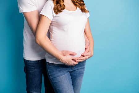 Cropped photo of young lovely happy couple family hug embrace man hold woman belly isolated on blue color backgroundの写真素材