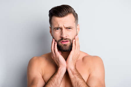 Photo of young handsome man unhappy sad upset displeased problem hand touch beard isolated over grey color backgroundの写真素材