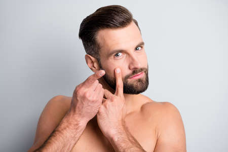 Photo of young handsome man put contact lens vision correction isolated over grey color backgroundの写真素材