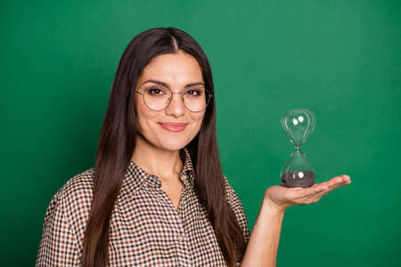 Photo of charming mature woman hold hourglass wear spectacles plaid shirt isolated green color...