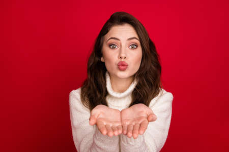 Photo of nice optimistic brunette lady blow kiss wear white sweater isolated on vivid red color...