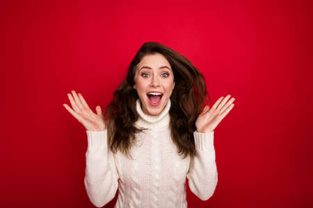 Portrait of attractive lucky cheerful amazed girl having fun great news isolated over bright red color backgroundの写真素材